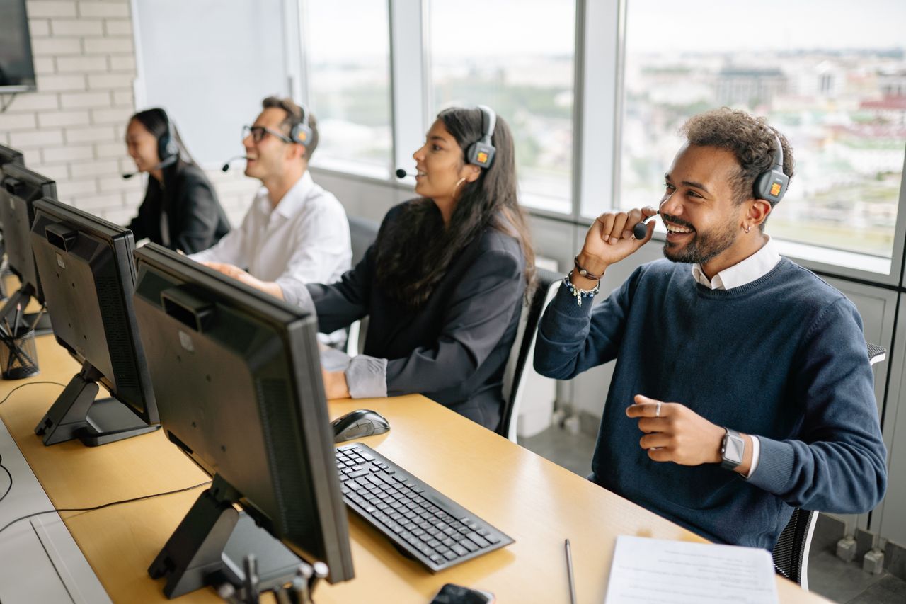 services-05 Group of diverse professionals working in a modern call center, engaging with clients through headsets.